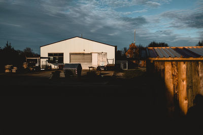 Houses by street amidst buildings against sky at dusk