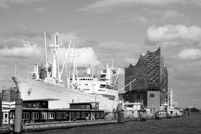 Sailboats moored at harbor against sky