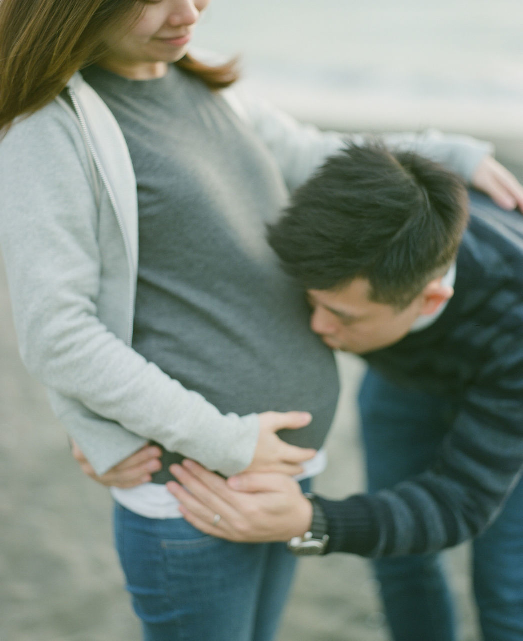 REAR VIEW OF COUPLE STANDING ON A WOMAN