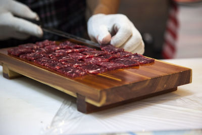 Midsection of man cutting meat on chopping board in kitchen