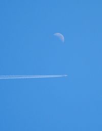 Low angle view of vapor trail against clear blue sky