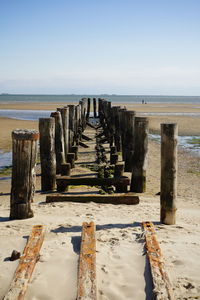 Wooden posts on beach against sky