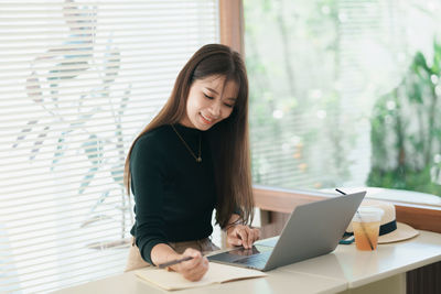 Portrait of young businesswoman using laptop at office