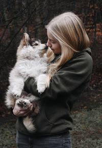 Blonde woman holding a puppy dog, kissing