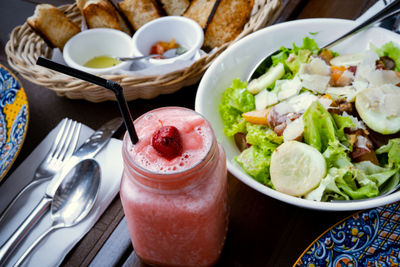 Strawberry shake, vegetable salad and bread on the table.