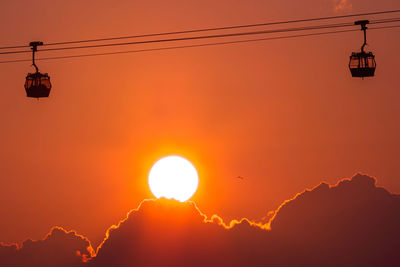 Low angle view of silhouette electricity pylon against sky during sunset