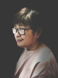 Smiling senior woman wearing eyeglasses against black background