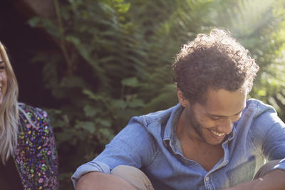 Happy man sitting with female friend against plant