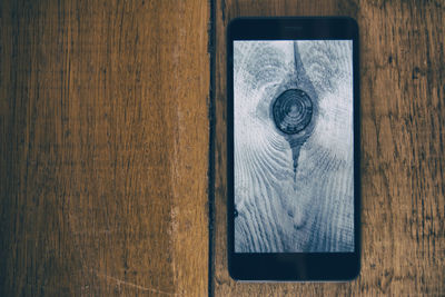 High angle view of smart phone on wooden table