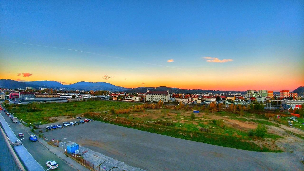 HIGH ANGLE VIEW OF ROAD BY CITYSCAPE AGAINST SKY DURING SUNSET