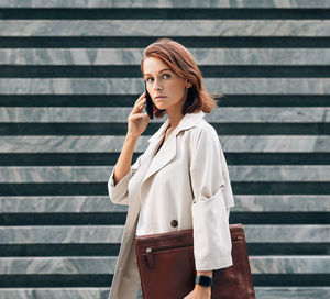 Young woman standing against wall