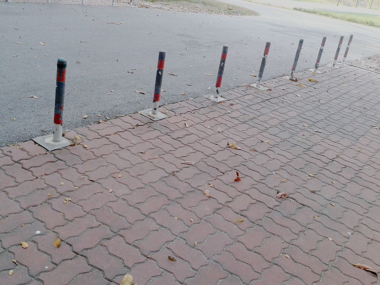 street, cobblestone, high angle view, road, asphalt, sidewalk, transportation, road marking, paving stone, footpath, day, outdoors, safety, pavement, red, protection, no people, pattern, in a row, guidance