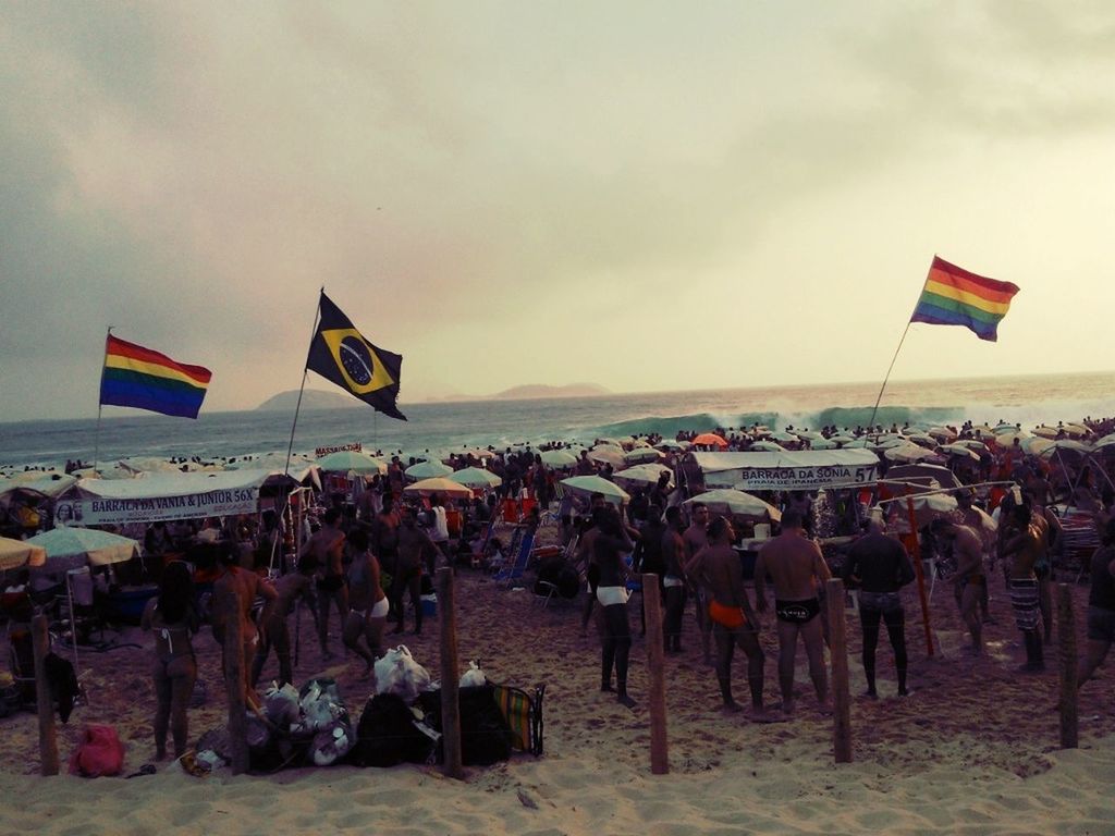 large group of people, lifestyles, leisure activity, sky, flag, men, patriotism, person, cloud - sky, beach, identity, mixed age range, national flag, vacations, tourist, enjoyment, sport, wind, transportation