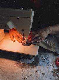 Cropped hand of woman sewing textile on machine