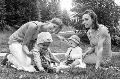 Smiling mothers with daughters relaxing at park