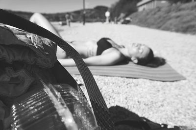 Close-up of shoulder bag against woman resting at beach