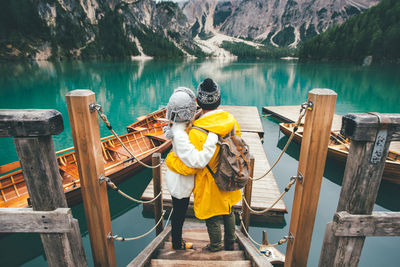 Rear view of men standing on railing by lake