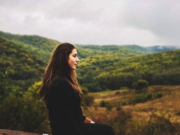 Woman looking away against land