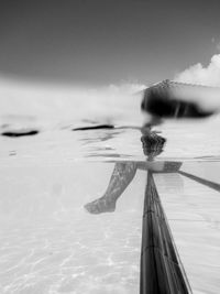 Reflection of person in swimming pool against sea