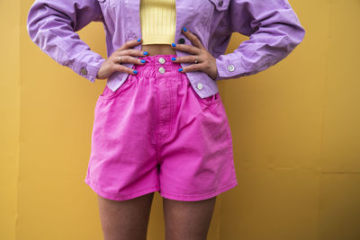 Woman with hands on hips in front of wall