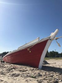 Ship moored on beach against clear blue sky