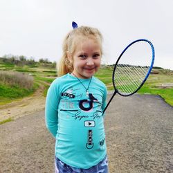 Portrait of girl holding badminton outdoors