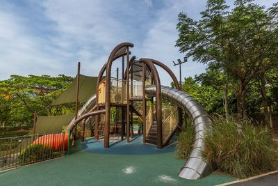 Metallic structure by swimming pool in park against sky
