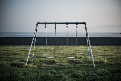 Swings on grass against horizon