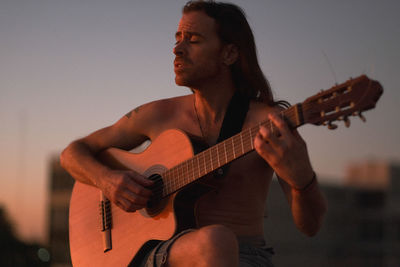 Guitarist singing and playing during sunset