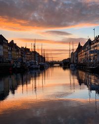 Sailboats moored at harbor against sky during sunset