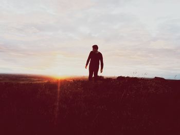 Man standing on field against sky during sunset