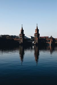 Reflection of church in river against clear sky