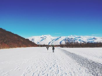 Scenic view of snow covered mountains against clear blue sky