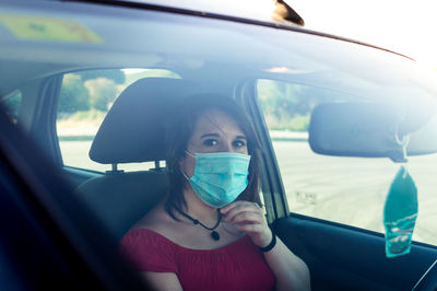 Portrait of woman wearing flu mask sitting in car