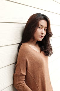 Close-up portrait of young woman standing against wall