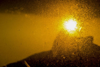 Close-up of illuminated yellow light against sky at night