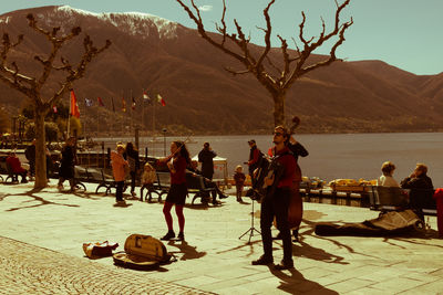 People on shore against mountains