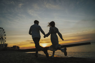 People on beach against sky during sunset