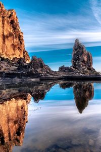 Rock formations by sea against blue sky