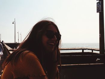 Portrait of smiling woman in sunglasses at sea against clear sky