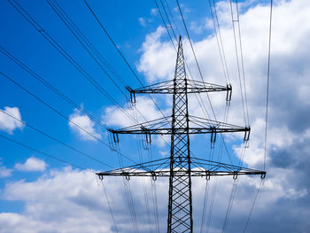 Low angle view of electricity pylon against blue sky