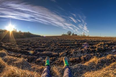 Low section of man resting on field against sky