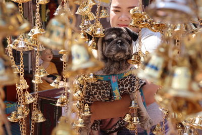 Close-up of woman carrying dog while buying golden bells in market