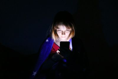 Young woman looking away while using phone at night