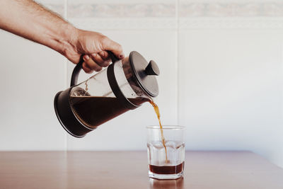 Close-up of hand pouring coffee in glass