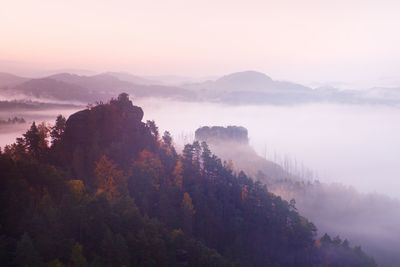 Fall valley of bohemian switzerland park. hill with hut on hill increased from magical darkness.