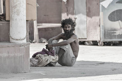 Portrait of young man sitting against building