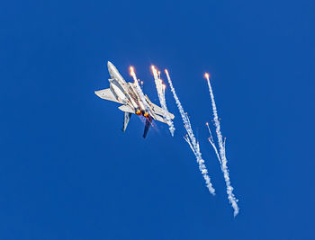 Low angle view of bird flying against clear blue sky