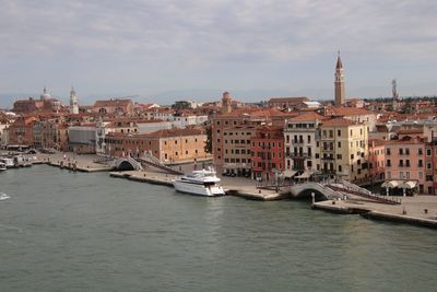 View of buildings at waterfront against cloudy sky