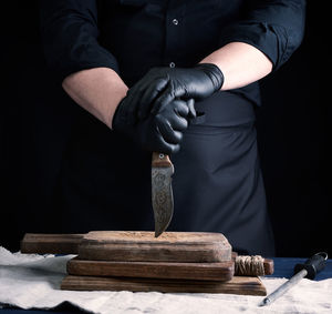 Midsection of man working on wood against black background